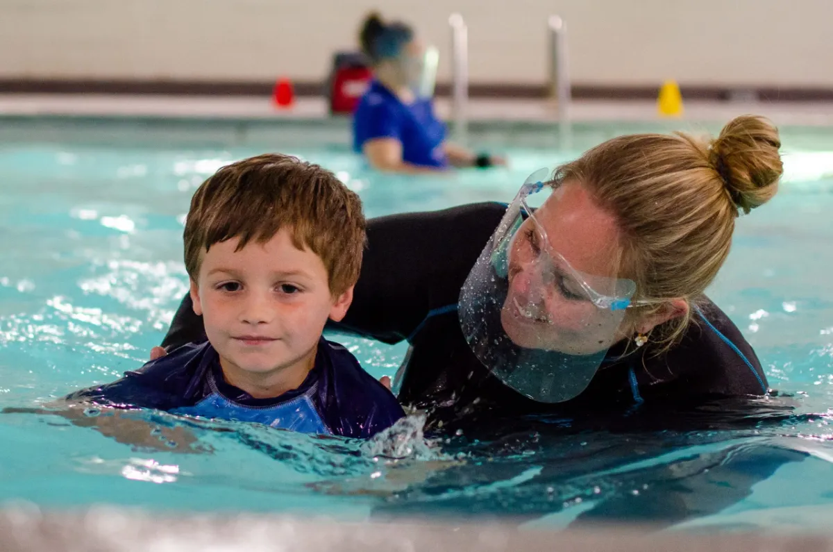 A Superfish instructor guiding a young swimmer during a private lesson